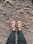 Top view shot of female legs in cream sneakers on the sand, walk on a sandy beach