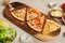Top view shot various kinds of delicious tasty juicy thin crispy cheesy sliced Italian pizza placed on wooden cutting board on