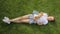 Top view shot of young girl lying on grass at park with book and caressing red cat