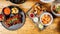 Top view of shrimps, fried food, salads, and sauces on trays on the table