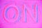 top view of on sign on pink neon