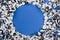 Top view of silver circle made of confetti on blue background.