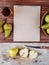Top view of a sketchbook and fresh ripe pears with a glass of pear juice on wooden background