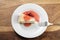 Top view of slice of traditional new york cheesecake with strawberry jam on white plate on wood table