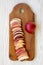 Top view, slices of fresh red apples on rustic wooden board on white wooden table. Flat lay, overhead, from above. Close-up