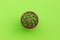 Top view of small cactus in green pot on lime color background.