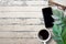Top view with smartphone,glasses,cup of coffee and green leave on wood table background