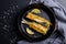 Top view of smelt fish on frying pan with lemon