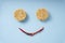 Top view - Smiling face made of instant noodles and spice chilli over blue background
