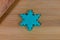 Top view of a snowflake made from blue plasticine on a wooden table