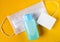 Top view of soap, medical surgical mask and hand sanitizer on  yellow background