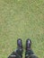 Top view, soldier in training uniform and combat boots standing on green grass.