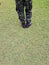 Top view, soldier in training uniform and combat boots standing on green grass.
