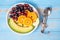 Top view spoon and fork, black grapes, red grapes, Valencia orange and melon fruits in white dish with pink Measuring tape on blue