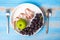 Top view spoon and fork, green apple and black grapes in white dish with pink Measuring tape on blue wood table background.