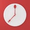 Top view of Spoon and fork on white round plate in a form of clock on red background. minimal food idea concept. Idea creative to