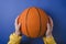 Top view of sportsman hands who holding basketball against blue background