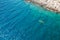 Top view of sportsmen or tourists kayaking in the turquoise transparent blue water of Adriatic sea rocky shore