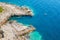 Top view of sportsmen or tourists kayaking in the turquoise transparent blue water of Adriatic sea rocky shore