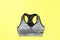 Top View of Sportswear Clothing. Women is Black and Gray Sports Bra Isolated on Yellow Color Pastel. Sport Accessories and Fashion
