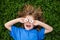 Top view spring child portrait. Funny kid smile and lay on grass. Outdoor funny face of little boy lying on fresh green