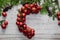 Top view of stages of making Christmas wreath with fir branches and decorative red balls on wooden rustic tabletop