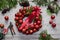 Top view of stages of making Christmas wreath with fir branches and decorative red balls on wooden rustic tabletop