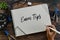 Top view of stationery,clock,glasses,plant and hand holding pen writing Exam Tips on notebook on wooden background