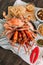 Top view of steamed Flower Crabs and Grilled Prawns Shrimps with Crab Cracker on paper with other seafoods in background