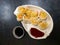 Top view of steamed vegetable and shrimp springrolls on a plate, on textured black table in restaurant. Dish is accompanied by