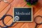 Top view of stethoscope,magnifying glass,plant and blackboard written with Medicaid on wooden background. Health concept.