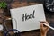 Top view of stethoscope,plant, clock and hand holding pen writing Heal on notebook on wooden background