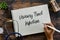 Top view of stethoscope,plant,sand clock, and hand holding pen writing Urinary Tract Infection on notebook on wooden background