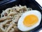 Top view of Stir fried Golden Mushroom or Enokitake with butter and boiled egg in black plate