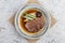 Top view of Streamed beef tounge gyutan served with shiitake, Japanese scallion and chilli with soup in rounded stone plate.