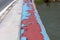 Top view of strong metal fence with cracked blue paint on local bridge surrounded with road on one side and river on other