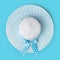 Top view summer beach round straw azure hat with spotted bow ribbon isolated in light blue background
