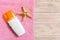 Top view of summer beach staff with copy space. Seashells or seastar, a bottle of suncream and pink towel on wooden background.