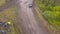 Top view of SUVs driving on country road. Clip. Off-road race on rural forested area on dirty ground