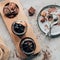 top view of sweet homemade desserts in glass jars and chocolate pieces