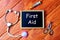 Top view of syringe,stethoscope, and blackboard written with first Aid on wooden background.Health concept.