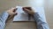 Top view of the table where there is a clean notebook. Women`s hands hold a pen