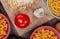 top view of tagliatelle macaroni with flour garlic and tomato on cutting board with other types of pasta on wooden background