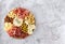 Top view of tasty charcuterie board with cheese, grape, nuts, olives, and ham on a circle kitchen plate