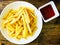 Top view of tasty french fries or potato fries with ketchup on wooden table