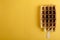 Top view of tasty fried waffle on the stick, yellow backgroun.Empty space for text