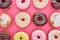 Top view of tasty glazed colorful doughnuts on bright pink background.