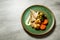 top view on tasty hake fillet with vegetables and sauce served on green plate