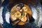 Top view on tasty sauteed seafood in a creamy sauce served in dark bowl. Shrimp, scallops, mussels, octopus in a dark plate. Close