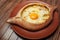 Top view on tasty traditional Adjarian Khachapuri - open baked pie with melted salt cheese suluguni and egg yolk on